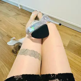 Glasklarer Plateau-High Heel auf Lady Samanthas Oberschenkeln mit Spitzenrock und ihrem Oberschenkel-Bandtattoo - Fussfetisch Zürich