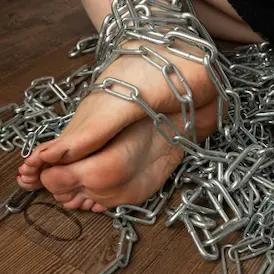 Sohlen von Lady Samanthas nackten Füssen mit roten Zehennägeln, in schweren Metallketten gefesselt - Fussfetisch Zürich